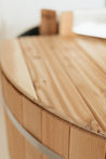 Close-up of a smooth cedar lid on a hot tub, showcasing its natural wood grain and rounded edges.