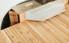 Cedar wood drink tray with a stainless steel edge, resting on a wooden surface.
