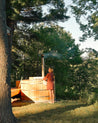 Person standing next to a wooden hot tub in a forested area