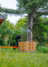 Person using a wooden hot tub in a forest setting
