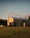 Wooden cabin in a field with a sunset sky