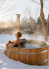 Woman relaxing in a wooden hot tub outdoors in winter