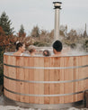 Cedar hot tub with four people relaxing inside, steam rising in a tranquil outdoor setting.