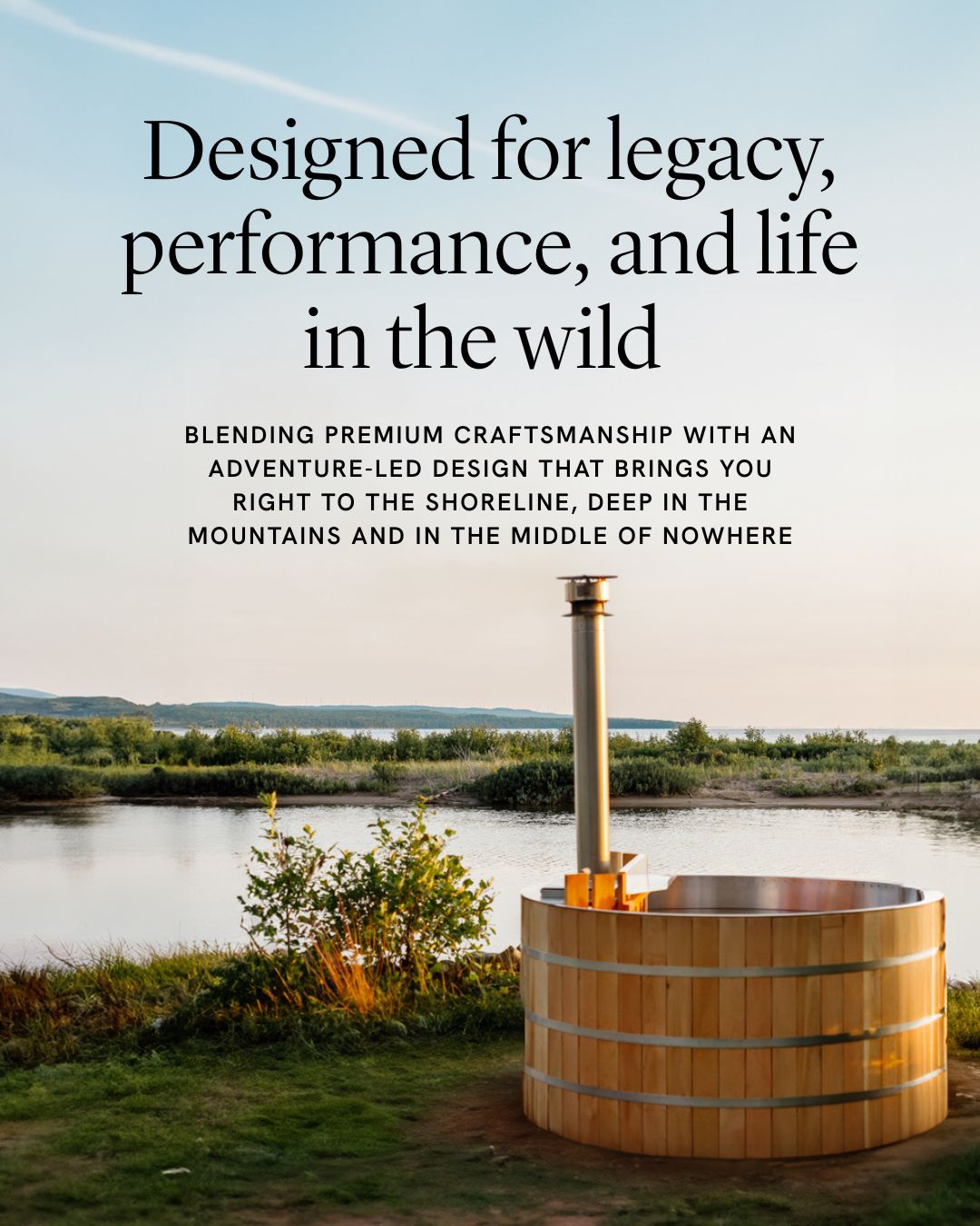Cedar wood fired hot tub beside a river, featuring a stainless steel chimney and natural surroundings.