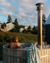 Person in a wood fired hot tub outdoors with a scenic background