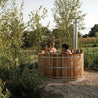 Hybrid wood hot tub amongst trees with women in it