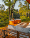 Outdoor hot tub with wooden deck and fire pit surrounded by trees