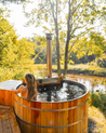 Person in a cedar hybrid hot tub surrounded by nature