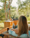 Woman reading a book by a hot tub in a forest setting