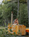 Man working on a wooden hot tub in a forest setting