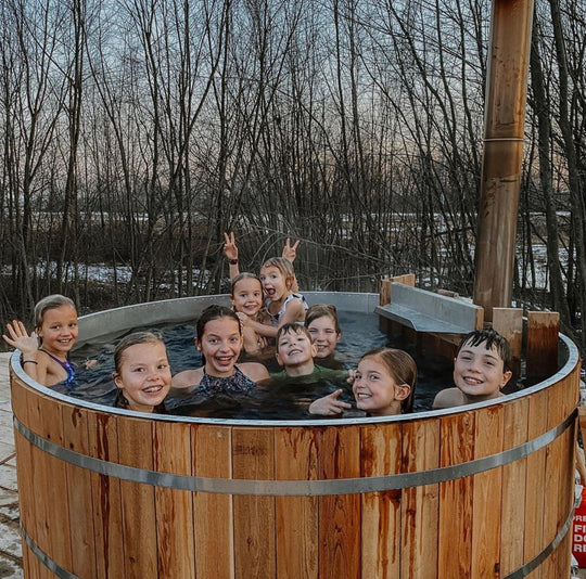Kids are sitting in an alumitubs wood fired hot tub